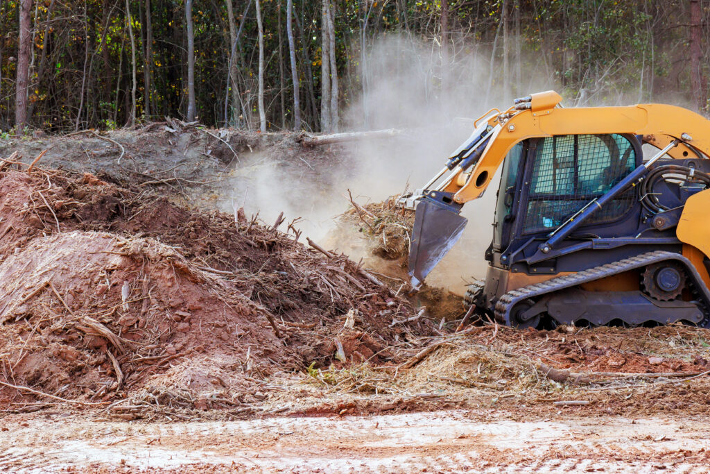 During construction, an earthmoving small mini tractor is leveling a ground land clearing in mobile al
