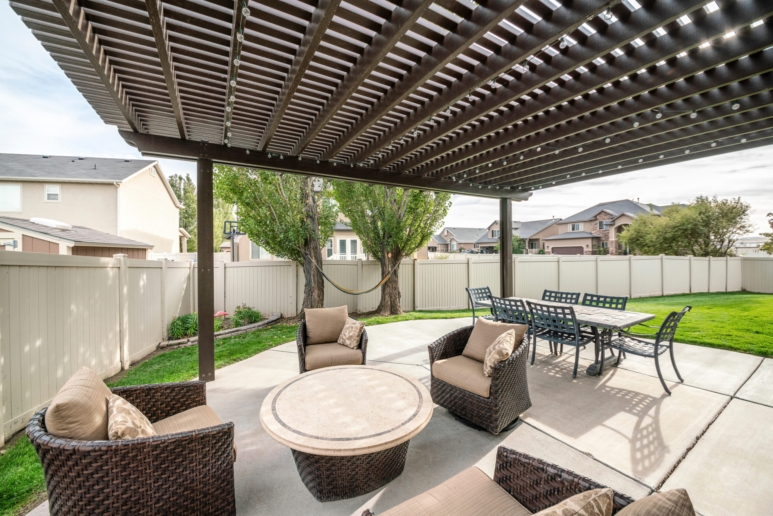 Woven armchairs with cushion and dining table under the pergola roof pergolas and decking installation