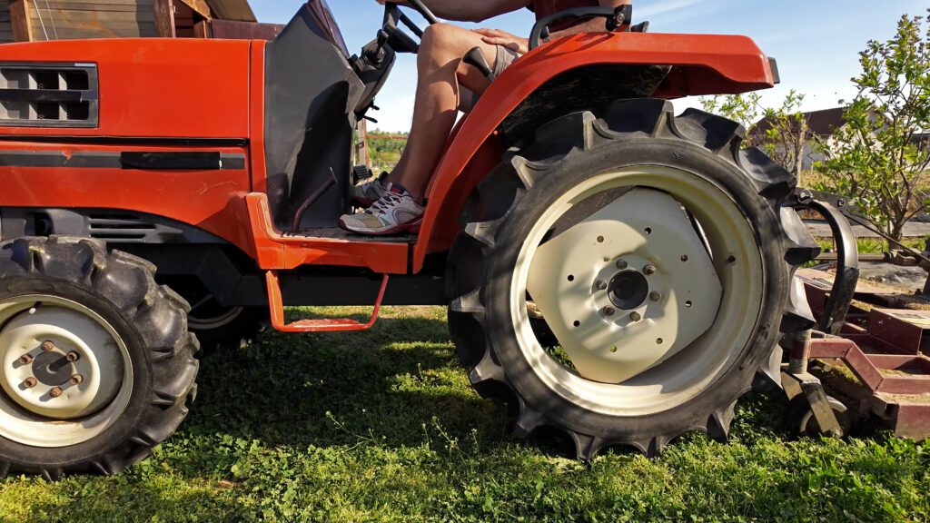 Farmer using bush hog on a tractor to cut weeds in a blueberries plant plantation. bush hogging in Mobile AL